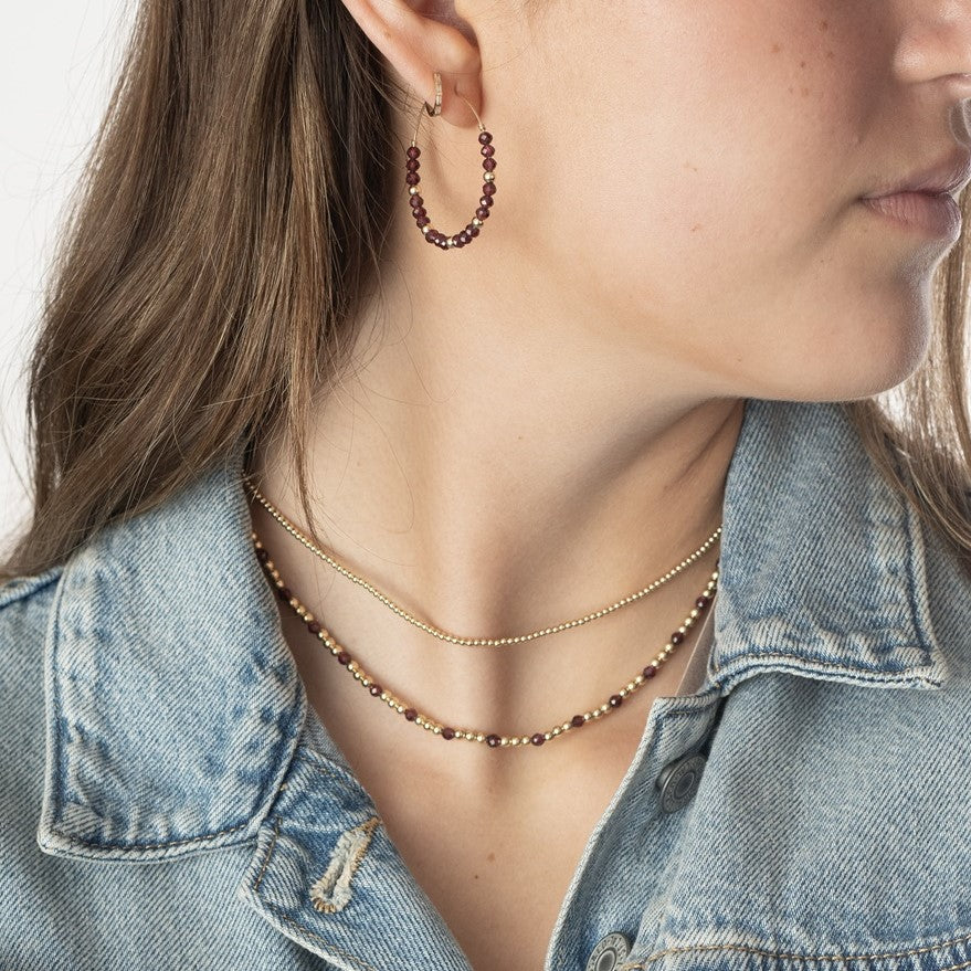 Model wearing 2 gold-filled beaded and garnet gemstone necklaces