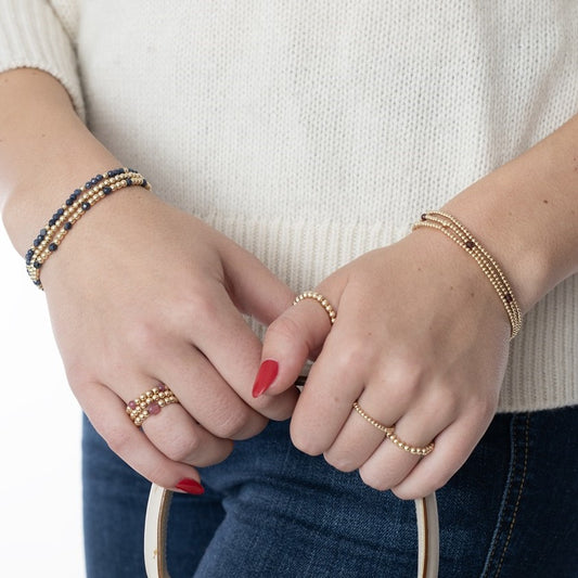 Model wearing gold filled bracelets and rings on each wrist and hand
