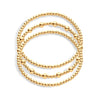 A stack of three bracelets, with varying sizes of beads in gold on a white background.