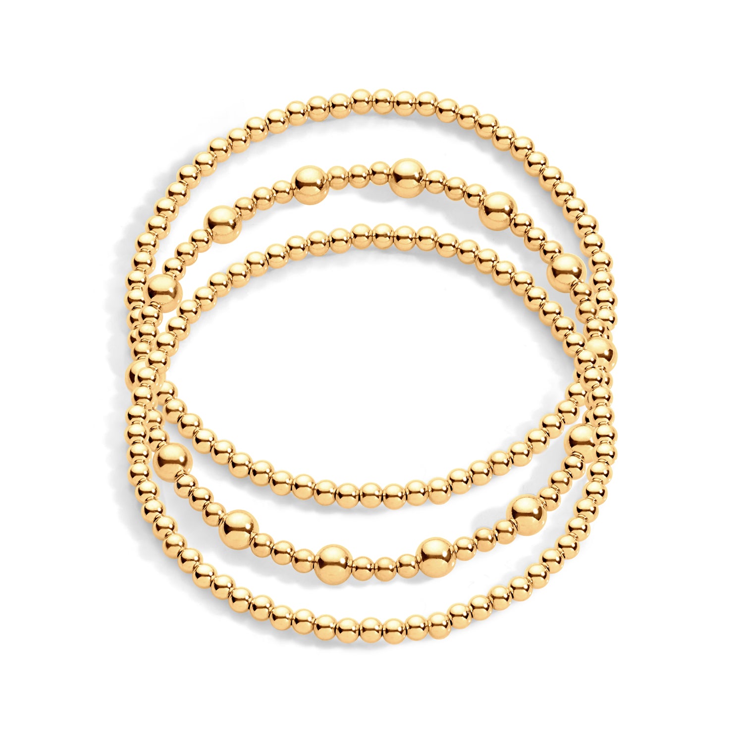 A stack of three bracelets, with varying sizes of beads in gold on a white background.