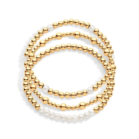 A set of three bracelets, featuring gold-filled beads and pearls, arranged to form a stack.