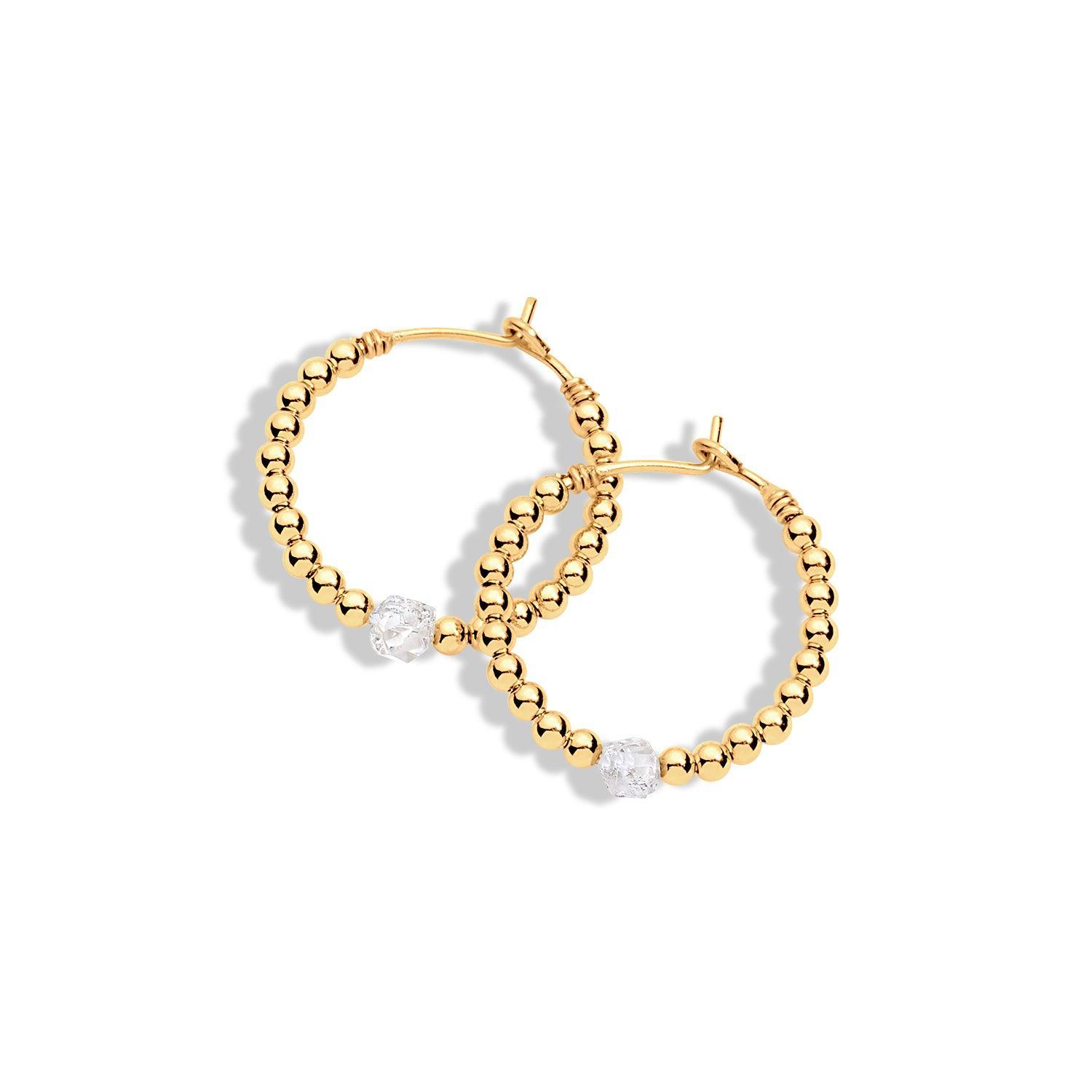 A pair of gold-filled hoop earrings with diamond gemstones and gold beads