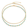 Two-layered gold-colored necklace with turquoise semi-precious gemstones and 14k gold-filled beads, displayed against a white background.