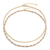 Two-layered gold-colored necklace with purple semi-precious gemstones and 14k gold-filled beads, displayed against a white background.