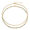 Two-layered gold-colored necklace with green semi-precious gemstones and 14k gold-filled beads, displayed against a white background.