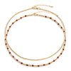 Two-layered gold-colored necklace with garnet semi-precious gemstones and 14k gold-filled beads, displayed against a white background.