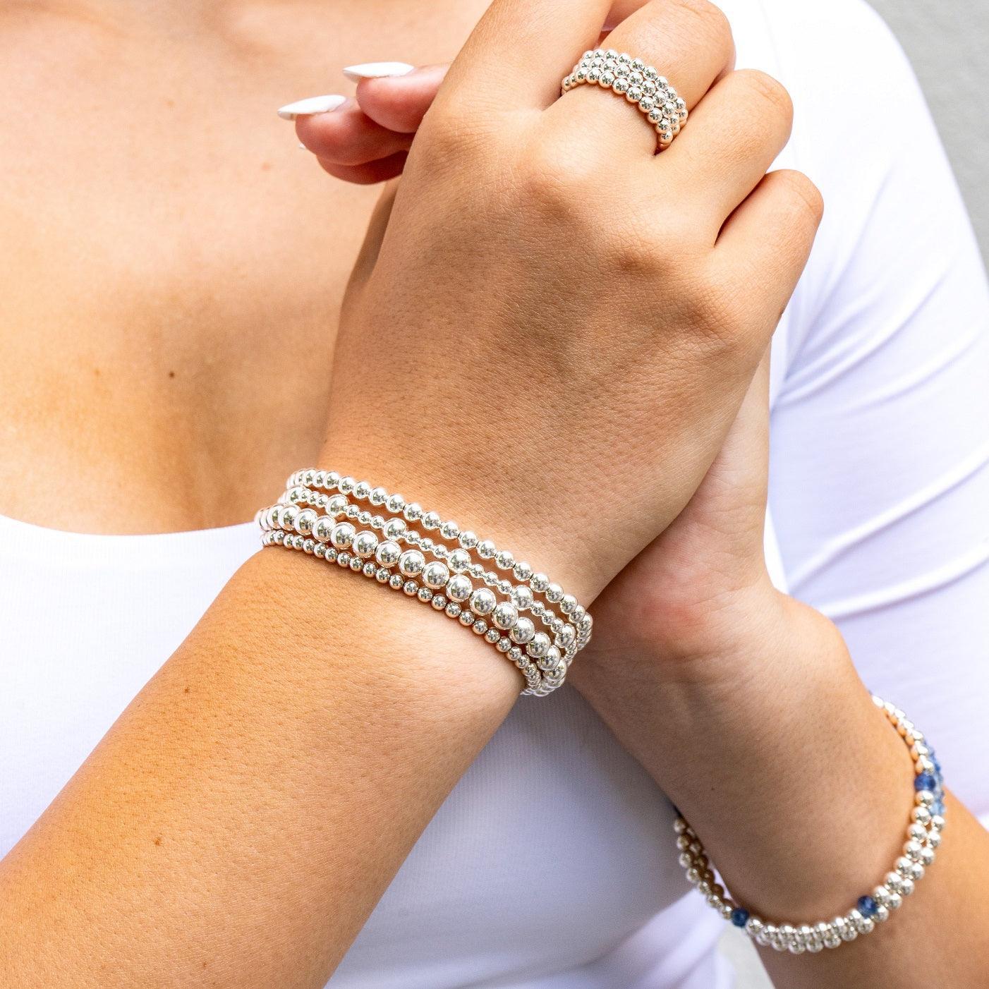 Model wearing sterling silver beaded bracelets stacked on wrist