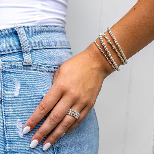 Model wearing sterling silver beaded bracelets stacked on wrist