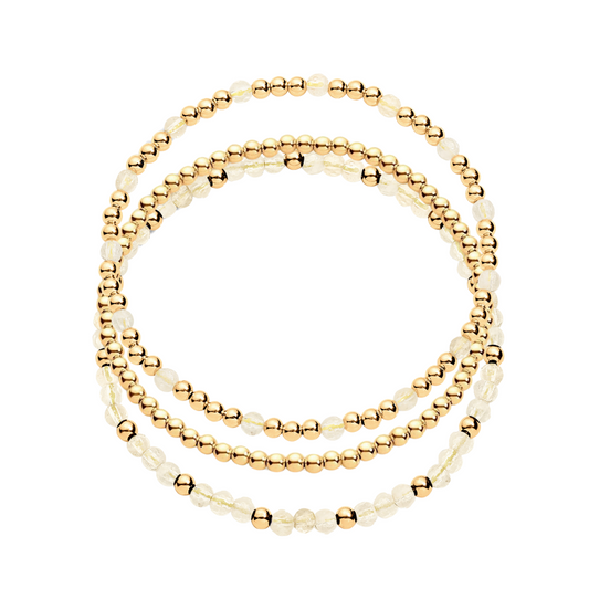 A stack of three bracelets, one featuring gold-filled beads and another with gold-filled beads and citrine gemstones.
