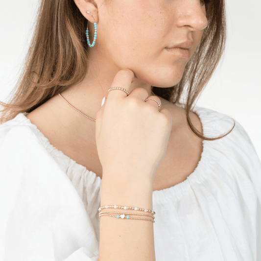 Model wearing gold bracelets and rings 