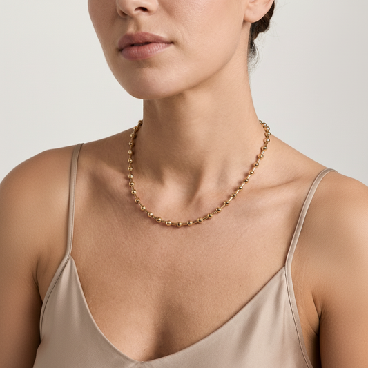 Woman wearing a gold necklace against a neutral background