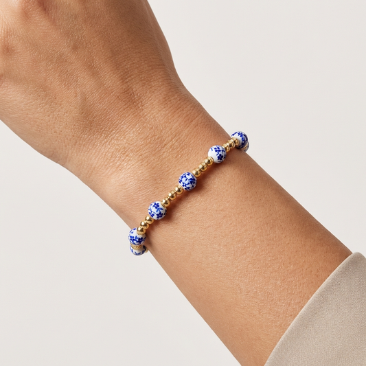 Bracelet with blue and gold beads on a wrist against a neutral background