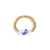 Gold beaded ring with a blue and white ceramic bead and two pearls on a white background