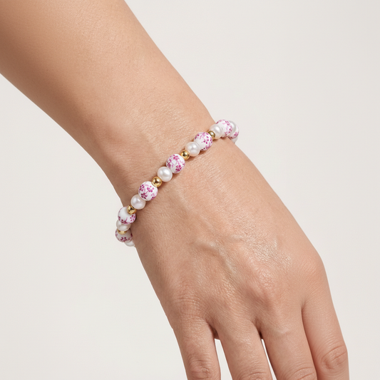 Hand wearing a pink beaded bracelet on a light background