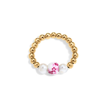 Gold beaded ring with a pink floral bead and a pearl on a white background