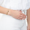 model wearing 3 gold filled bracelets, one with pearls and one with a gold cross
