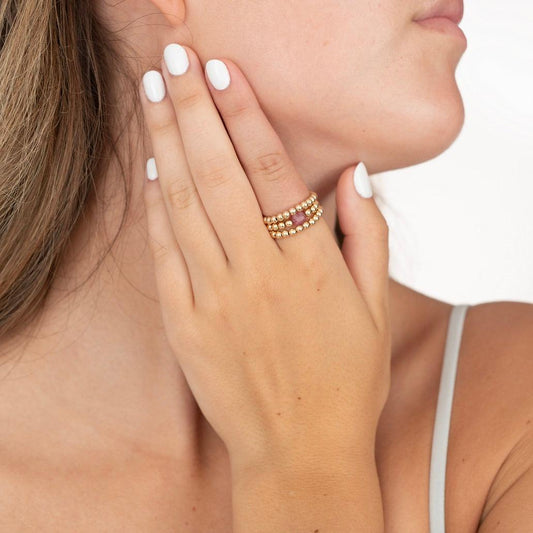 model wearing gold filled beaded rings with pink gemstone