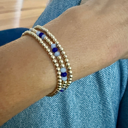 Gold beaded bracelet on a wrist with a denim background