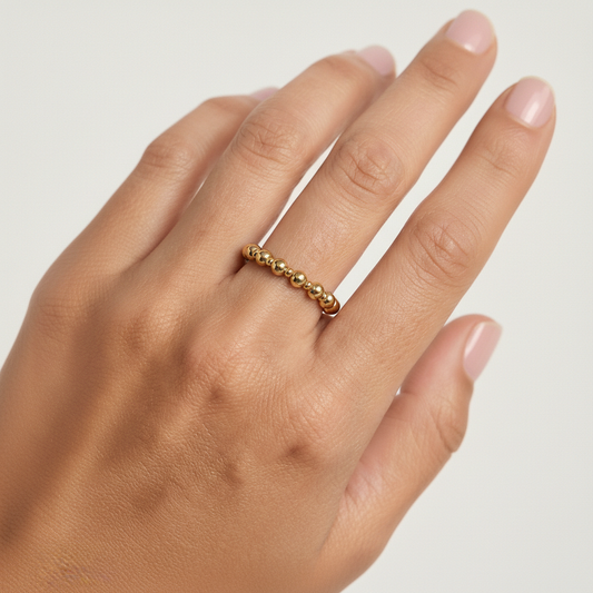 Gold ring on a hand against a plain background