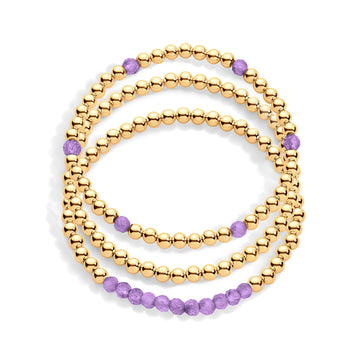 A stack of three gold & amethyst gemstone bracelets