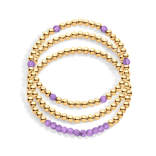 A stack of three gold & amethyst gemstone bracelets