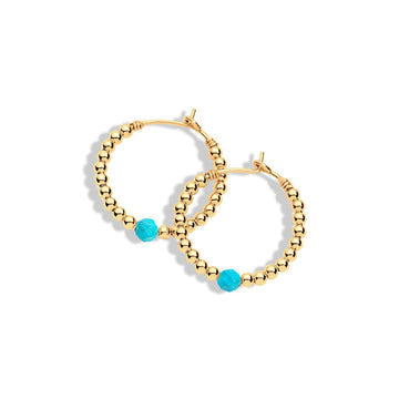 A pair of gold-filled hoop earrings with small turquoise gemstones attached to them.