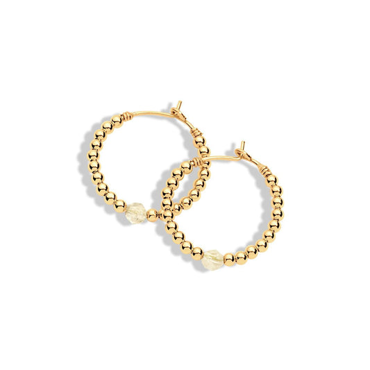 A pair of gold-filled hoop earrings with small yellow gemstones attached to them.