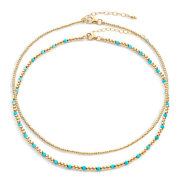 Two-layered gold-colored necklace with turquoise semi-precious gemstones and 14k gold-filled beads, displayed against a white background.
