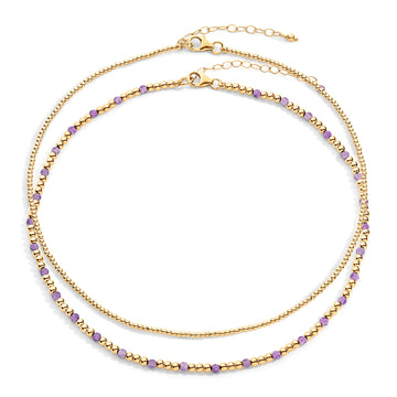 Two-layered gold-colored necklace with purple semi-precious gemstones and 14k gold-filled beads, displayed against a white background.