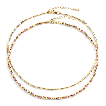 Two-layered gold-colored necklace with pink semi-precious gemstones and 14k gold-filled beads, displayed against a white background.