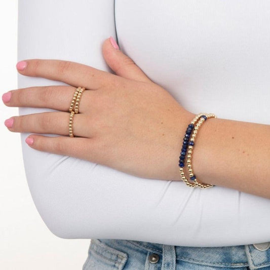 Model wearing gold filled beaded bracelet with gemstones and rings